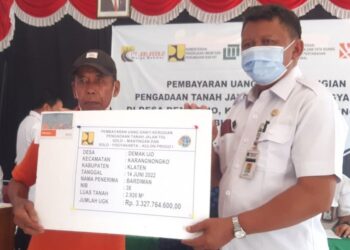 BARDIMAN (kiri) menerima pampasan paling tinggi bagi pengambilan tanah di Kampung Demakijo, Kecamatan Karangnongko, Jawa Tengah.-KOMPAS