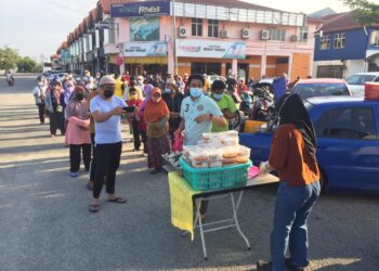 MOHD. Hafizi CM Hatta (tengah, baju hijau muda) membuat pengagihan kira-kira 300 pek makanan percuma di Perkampungan Sungai Isap Jaya di Kuantan, Pahang. - UTUSAN/DIANA SURYA ABD WAHAB