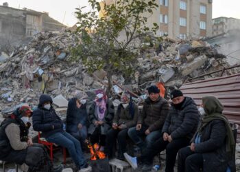 PENDUDUK yang masih menunggu berita tentang ahli keluarga mereka yang hilang akibat gempa bumi duduk berhampiran runtuhan bangunan di Hatay di Turkiye.-AFP
