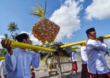 BEBERAPA lelaki mengangkat hiasan juadah untuk disajikan kepada tetamu tradisi lebaran ketupat di pantai Batulayar, Lombok Barat.-AGENSI