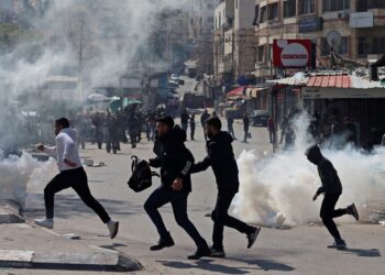 PENDUDUK Palestin mengelak daripada terkena gas pemedih mata yang dilepaskan oleh tentera Israel ketika serbuan di bandar Nablus, Tebing Barat. - AFP