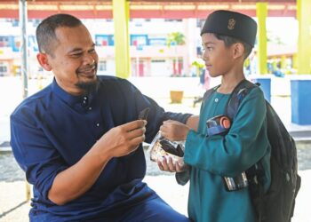MUHAMMAD Farish Syakib Mohd. FadliSham menghadiahkan kek kecil yang disediakan ibunya kepada seorang guru sempena Hari Guru di SK Padang Mengkuang, Marang, semalam. - UTUSAN/PUQTRA HAIRRY ROSLI