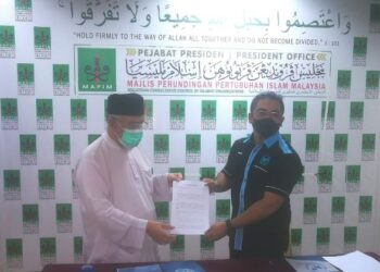 MOHD. Azmi (kiri) dan Hishammuddin menunjukkan MoU yang ditandatangani mereka sebagai komitmen memperjuangkan isu tahanan tanpa negara di Sabah di Shah Alam, Selangor. - UTUSAN / ABDUL RAZAK IDRIS