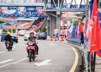 KENDERAAN melintasi deretan bendera parti politik yang bertanding pada Pilihan Raya Umum Ke-15 (PRU15) 19 November ini ketika tinjauan  di Jalan Datuk Keramat, Kuala Lumpur, semlam. – Utusan/FARIZ RUSADIO