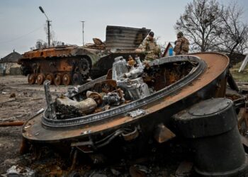 ANGGOTA tentera Ukraine berdiri di tepi kapal pengangkut peribadi berperisai yang musnah di kampung Petropavlivka di wilayah Kharkiv.-AFP