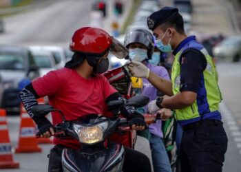 SEORANG anggota polis melakukan pemeriksaan ketika sekatan jalan raya di Persiaran Puncak Jalil, Kuala Lumpur, baru-baru ini. - GAMBAR HIASAN