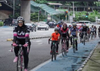 Sekumpulan penunggang basikal melalui Jalan Ampang di Kuala Lumpur yang sibuk dengan kenderaan. – UTUSAN/FARIZ RUSADIO