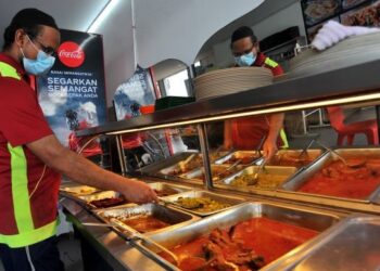 SEORANG pekerja memeriksa lauk yang dijual di Restoran Masyur, Taman Pelangi, Johor Bahru. - UTUSAN/RAJA JAAFAR ALI
