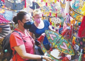 PELANCONG asing, Nicola Brookes (kanan) dari England bersama rakannya, Rebecca DuFauly dari Amerika Syarikat tertarik melihat wau tradisional Malaysia yang dijual di Pasar Seni Kuala Lumpur. - UTUSAN/FAUZI BAHARUDIN