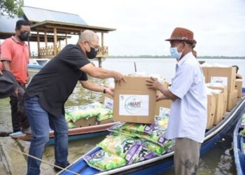 RONALD Kiandee (dua kiri) menyampaikan bantuan MAFI Prihatin kepada salah seorang penerima di Beluran hari ini.