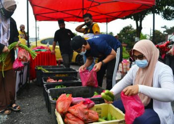 BEBERAPA kakitangan sebuah syarikat guaman mengagihkan barangan basah percuma termasuk sayur kepada penduduk di Masjid Tanah, Melaka, semalam. - UTUSAN/DIYANATUL ATIQAH ZAKARYA