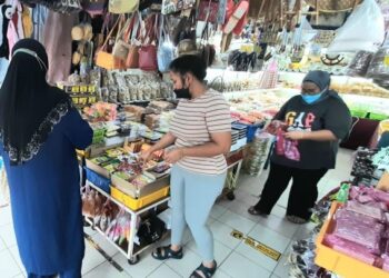 SYAHIRAH Abdullah (tengah) melayan pelanggan di Medan Samudera, Banda Hilir, Melaka. - UTUSAN/AMRAN MULUP