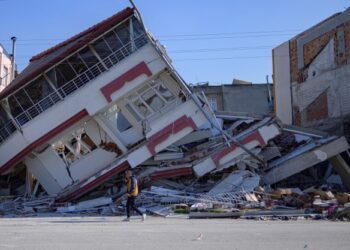 PENDUDUK berjalan di sebelah bangunan yang runtuh di Samandag, Hatay akibat kejadian gempa bumi minggu lalu. - AFP 