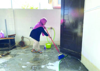 ROSLINDA Jaafar membersihkan rumahnya di Kampung Sri Gading, Batu Pahat selepas dibenarkan pulang setelah menghuni PPS Sekolah Agama Sri Gading selama dua minggu.