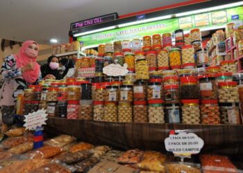 NURLINA Muhamad (kiri) bersama ratusan balang kuih raya yang dijual kepada pengunjung bagi menyambut Hari Raya Aidilfitri di Angsana Mall Johor Bahru, Johor. - UTUSAN/RAJA JAAFAR ALI