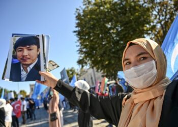 SEORANG wanita Uighur menunjukkan gambar ahli keluarganya yang ditahan China dalam satu demonstrasi di Istanbul, Turki. - AFP 