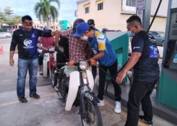 ABAM Paeh (dua dari kanan) membantu mengisi petrol penunggang motosikal di sebuah stesen minyak di Taman Guchil Jaya, Kuala Krai, Kelantan.-UTUSAN/ROHANA MOHD.NAWI