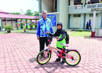 ABD. Manaf Mat bersama murid yang rajin ke sekolah, Nur Yasmeen Alias selepas menerima hadiah sebuah basikal di Kampung Bantal, Ulu Tembeling di Jerantut, Pahang. – UTUSAN/HARIS FADILAH AHMAD