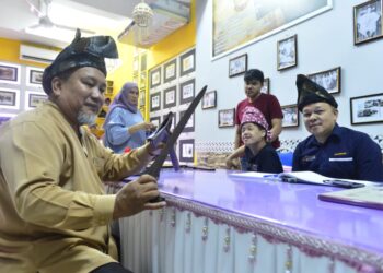 MOHD. Alhamadi Abu Bakar (kiri) menunjukkan keris peninggalan pahlawan Melayu, Mat Kilau kepada pengunjung Galeri Mat Kilau di SK Padang Garuda di Kuantan, Pahang. - UTUSAN/SHAIKH AHMAD RAZIF