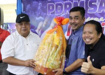 IDRIS Abdullah (kiri) menyampaikan hadiah kepada salah sebuah pasukan yang menang pertandingan boling di Kota Kinabalu semalam.