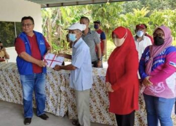 AWANG Lakat (kiri) menerima borang kemasukan ahli Umno daripada Baki Saban (tiga kanan) yang mengetuai kumpulan berkenaan di Kampung Tenambak, Kuala Penyu semalam.