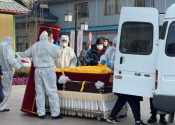 KAKITANGAN memindahkan mayat ke dalam keranda di rumah pengebumian di Beijing kelmarin.-REUTERS