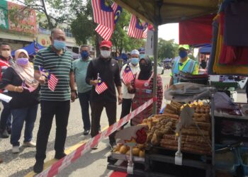 HAMDAN Hussin (empat, kanan) mengagihkan Jalur Gemilang kepada peniaga di tapak niaga di Sungai Isap di Kuantan pada 28 Ogos 2021. - FOTO/DIANA SURYA ABD WAHAB