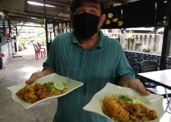 MOHD. Arif Abdullah yang cacat penglihatan menunjukkan nasi goreng sotong emas yang dijual di kedainya di Kampung Balai Besar di Dungun. - UTUSAN/NIK NUR IZZATUL HAZWANI NIK ADNAN