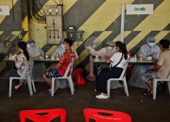 PETUGAS perubatan membuat semakan sebelum orang ramai menerima suntikan vaksin AstraZeneca atau CoronaVac di luar stadium bola sepak tertutup di Bangkok. -AFP 