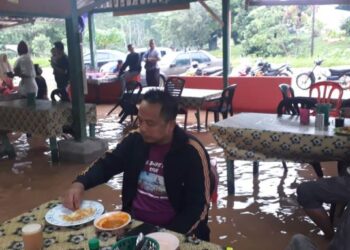 BEBERAPA orang pelanggan sedang bersarapan di sebuah kedai roti canai yang dinaiki air banjir kilat di Kampung Baharu di Jerantut, Pahang. - FOTO /IHSAN PENDUDUK KAMPUNG BAHARU