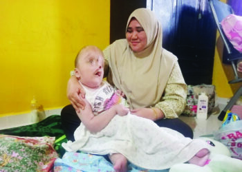 WAN Nora Wan Nawi memangku Nursyazwana Mohd. Azri di Kampung Tok Bintang, Hulu Terengganu. – UTUSAN/NOOR HAYATI MAMAT