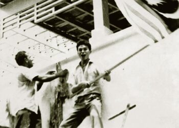 S. Samy Vellu (kiri) mengibarkan bendera Malaysia di Kedutaan Indonesia di Kuala Lumpur ketika krisis konfrontasi antara kedua-dua negara pada 1963.  – ARKIB UTUSAN