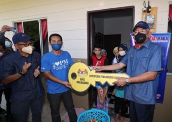 MAHDZIR Khalid (kanan) menyampaikan kunci replika sebagai simbolik penyerahan rumah PPRT kepada Ramlon (dua kiri) di Kampung Tanjung Batu di Kota Marudu semalam.