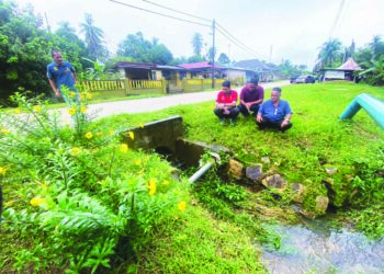 PENDUDUK meninjau pembentung yang kecil dan tidak cukup untuk menampung aliran air sekali gus menyebabkan berlakunya banjir kilat di Lorong 12 dan blok tiga peringkat satu Felda Bukit Goh di Kuantan, Pahang sejak lebih 20 tahun lalu. - UTUSAN/NORHAFIZAN ZULKIFLI