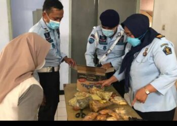 PEGAWAI Penjara Garut memeriksa makanan yang dibawa pengunjung kepada banduan. - AGENSI