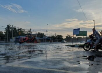 YIN Lei Hing menunggang motosikal bersama suaminya, Lee Chai melihat keadaan jalan utama yang dinaiki air apabila air laut dari Sungai Tengi di Tanjong Karang, Kuala Selangor, Selangor melimpah, hari ini. - UTUSAN / MOHAMAD ATHIR ISMAIL