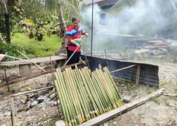 BAHARUDDIN Saaid mengawal bara api ketika memasak kelamai di Kampung Relong di Lipis, Pahang. - UTUSAN/HARIS FADILAH AHMAD
