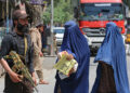 DUA wanita Afghanistan yang lengkap memakai burka berjalan di depan anggota keselamatan Taliban di Jalalabad. - AFP