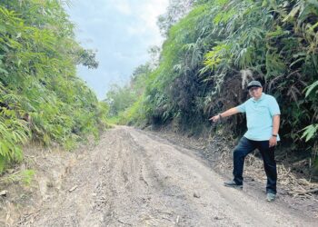 MOHD. Syahbuddin Hashim menunjukkan keadaan jalan yang masih belum dinaik taraf di Pos Hau, Gua Musang, Kelantan, semalam. - UTUSAN/AIMUNI TUAN LAH