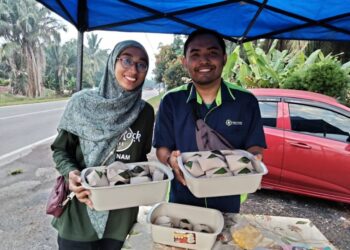 ZAINAL ABIDIN KASIMIN dan Nur Afiqah Zainuddin menunjukkan nasi lemak yang dijual pada harga RM1 di gerai mereka di hadapan Masjid Jamek Kampung Parit Semerah, Pontian.