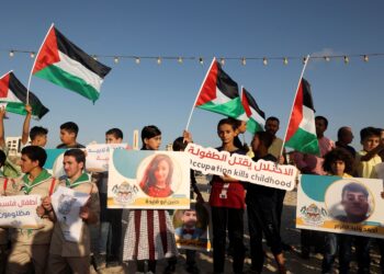 KANAK-KANAK Palestin memegang papan sepanduk tertera wajah kanak-kanak yang maut dalam serangan udara Israel di Semenanjung Gaza pada Ogos tahun lalu. - AFP