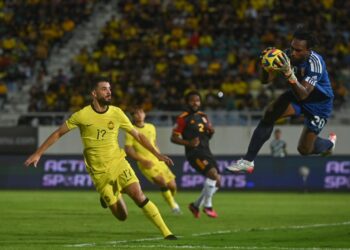 PENJAGA gol Papua New Guinea, Ronald Warisan (kanan) menyelamatkan bola percubaan pemain Harimau Malaya pada Perlawanan Persahabatan Tier 1 di Stadium Sultan Mizan Zainal Abidin, Gong Badak, Kuala Nerus, malam ini. - UTUSAN/PUQTRA HAIRRY ROSLI