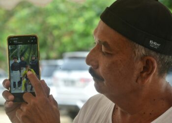 MASDI Md Isa menunjukkan gambar anaknya, Mohd. Iqmal (berbaju Melayu kuning) ketika ditemui pemberita di kediamannya di Kampung Rawa Lenggeng di Seremban hari ini.-UTUSAN/MOHD. SHAHEJAN MAAMIN.