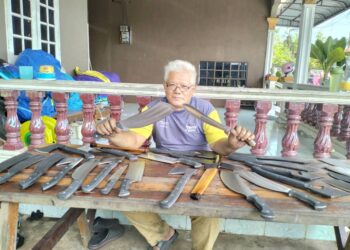 NASIR Mohamad menunjukkan pisau dan parang yang ditempah pelanggan di rumahnya di Kampung Gelugor Kedai, Kuala Terengganu, semalam. – UTUSAN/KAMALIZA KAMARUDDIN