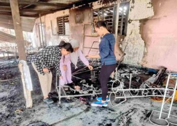 MAIMUNAH Ahmad (tengah) bersama dua anaknya memeriksa sisa kebakaran di  rumah mereka yang yang terbakar semalam di Kampung Esso Teluk Intan. – UTUSAN/AIN SAFRE BIDIN