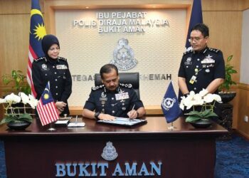 RAZARUDIN Husain menandatangani dokumen memulakan tugas rasmi Ketua Polis Negara yang baharu sambil disaksikan Noorsiah Mohd. Saaduddin (kiri) di Bukit Aman pagi tadi.