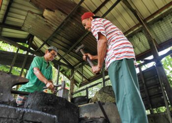 MAT Yusoff Saleh (kiri) bersama rakannya menempa bilah pisau di bengkelnya di Kampung Perangkap, Pasir Mas, Kelantan, semalam. 
–UTUSAN/KAMARUL BISMI KAMARULZAMAN