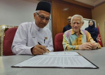 MUHAMAD Husain (kiri) menurunkan tandatangan sambil diperhatikan oleh Kamarudin Md. Nor pada Majlis Penyerahan Nota Serah Tugas Pengerusi KADA di Ibu Pejabat KADA, Kota Bharu, Kelantan hari ini.-UTUSAN/YATIMIN ABDULLAH
