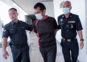 TERTUDUH diiring keluar anggota polis selepas mengaku bersalah di Mahkamah Majistret, Ayer Keroh, Melaka atas kesalahan menumbuk kepala dan menghempas badan bapa kandungnya ke tanah. - UTUSAN/SYAFEEQ AHMAD