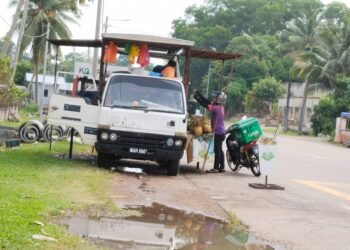 SEORANG penghantar makanan sedang mengambil pesanan pelanggan di Durian Tunggal, Melaka. - UTUSAN/MUHAMMAD SHAHIZAM TAZALI